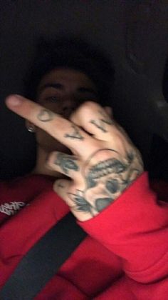 a man with tattoos making the peace sign