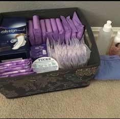 a black box filled with purple items on top of a carpeted floor next to a wall