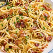 a plate full of pasta with bacon and parsley