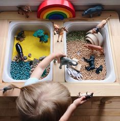 a young boy playing with toys in his toy kitchen drawer, which is filled with dirt and rocks