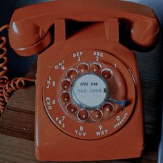 an orange telephone sitting on top of a wooden table