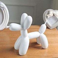 a white dog figurine sitting on top of a wooden table next to a mirror