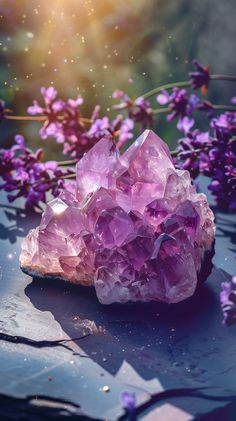 a cluster of pink crystals sitting on top of a table next to some purple flowers