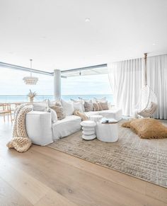 a living room filled with white furniture next to a large window covered in sheer curtains