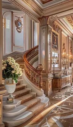 an ornate staircase with white flowers in a vase on the bottom and gold trimmings