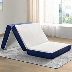 a blue and white bed sitting on top of a wooden floor next to a window