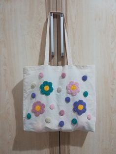 a white bag with flowers on it hanging from a door