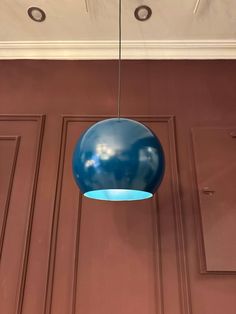 a blue ball hanging from the ceiling in front of a brown wall with two doors