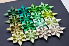 several origami flowers are arranged on a black surface with white and green paper