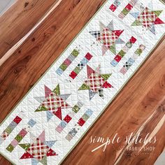 a quilted table runner with red, green and white plaid stars on the edge