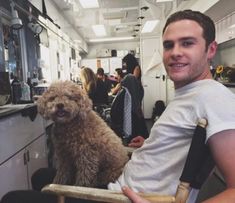 a man sitting in a chair with a dog on his lap and people behind him