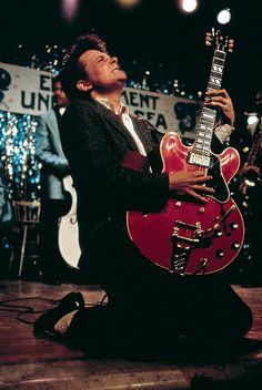 a man sitting on the floor playing an electric guitar