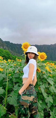 a woman standing in front of a field of sunflowers