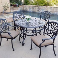 an outdoor table with four chairs and a pool in the backgroung area