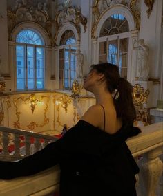 a woman standing in front of a railing with her hand on the railing and looking up