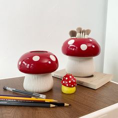 two red and white mushrooms with pencils on a table