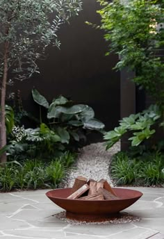 a large bowl sitting on top of a stone floor in front of some trees and bushes