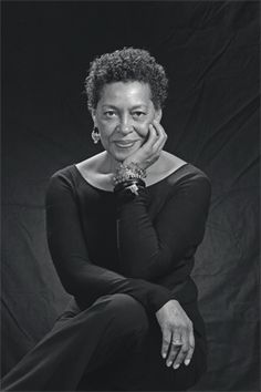 a black and white photo of a woman with her hands on her face, sitting in front of a black background