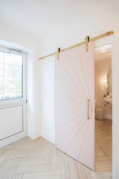 an open pink door in the middle of a room with wood flooring and white walls