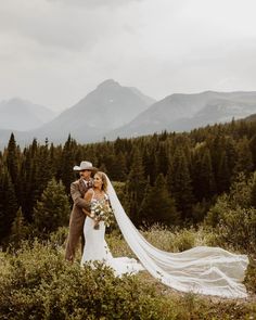 a bride and groom standing in the mountains