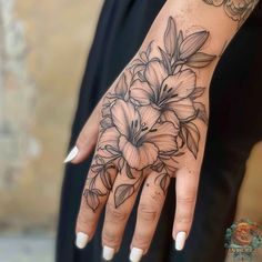 a woman's hand with tattoos and flowers on her left wrist, showing the ring finger