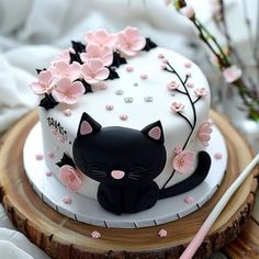 a white cake decorated with black cat and pink flowers