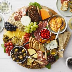 a platter filled with different types of cheeses, meats and crackers