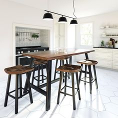 a kitchen table with four stools in front of it and an oven on the other side