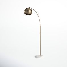 a floor lamp with a white base and a gold colored shade on the light bulb