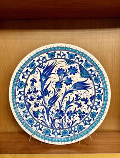 a blue and white plate sitting on top of a wooden shelf