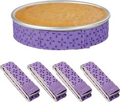 four pieces of cake sitting next to each other in front of a pie pan with purple icing