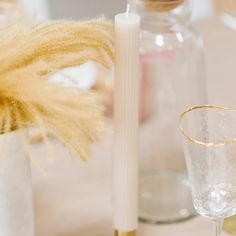 the table is set with glasses, candles and vases