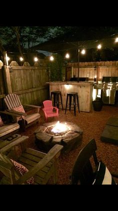 an outdoor fire pit surrounded by chairs and lights