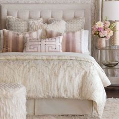 a bedroom with a large bed covered in lots of pillows and blankets, along with a mirror on the wall