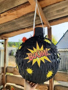 a person holding up a black bomb shaped object with the word boom written on it