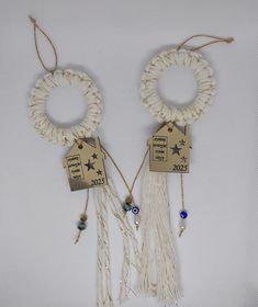 two white bracelets with tassels and beads hanging from each other on a white background