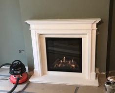 a white fireplace with a red blower sitting on the floor in front of it