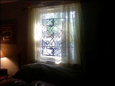 a bedroom with a window covered in curtains and light coming through the window sill