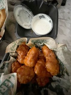 some chicken wings and dipping sauce in small trays