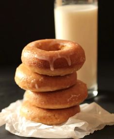 three donuts stacked on top of each other next to a glass of milk