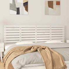 a white bed sitting in a bedroom next to two paintings