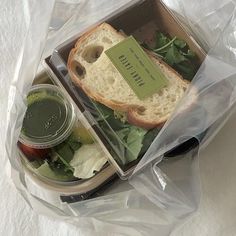 a sandwich in a plastic bag with lettuce and tomato