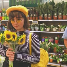 a woman holding sunflowers in front of a flower shop