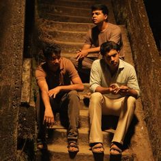 three men sitting on the steps in an old building