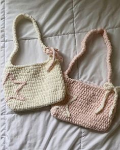 two crocheted purses sitting on top of a white bed next to each other