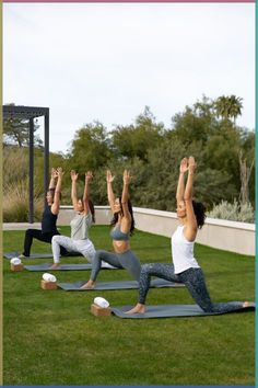 a group of people doing yoga outside in the grass with their hands up to the sky