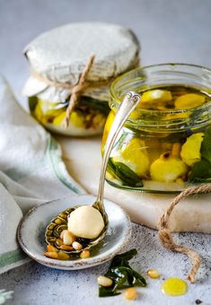 two jars filled with food sitting on top of a white plate next to a spoon