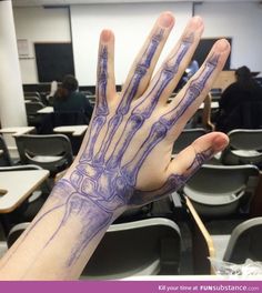 a person's hand with purple ink on it in front of a classroom full of desks