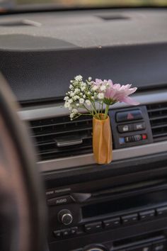 a small vase with flowers in it sitting on the dash board of a car's dashboard