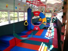 the inside of a school bus with colorful play mats and swings on the walls, windows, and doors